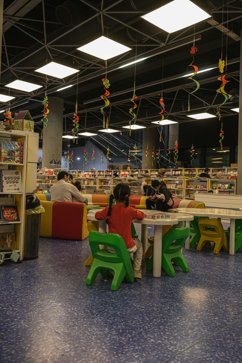 Niños jugando con juegos dentro de una biblioteca con decoraciones coloridas.